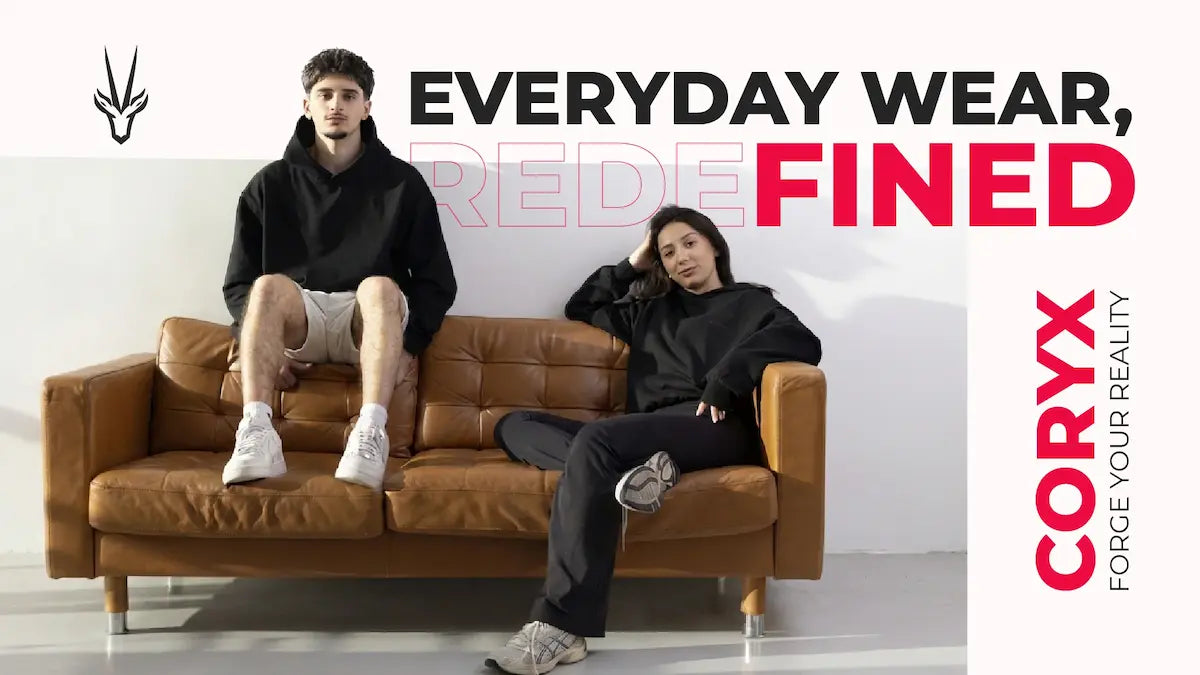 Two models posing on a brown leather couch in a studio setting, wearing black coryx hoodies and sweatpants. The image features promotional text overlays reading 'EVERYDAY WEAR, REDENED FINED' and 'CORYX FORGE YOUR REALITY'.